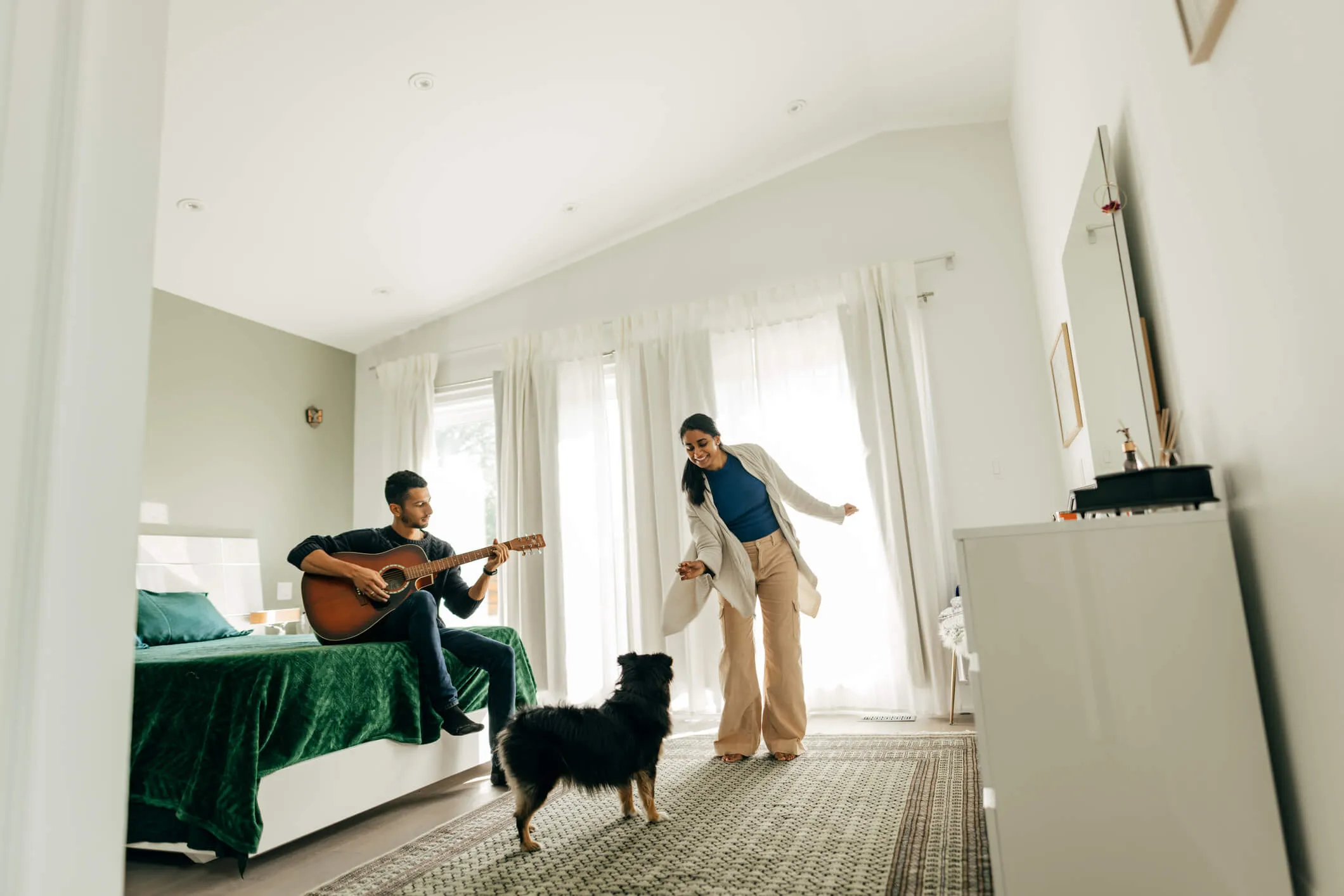 A man and women playing with their dog in their home.